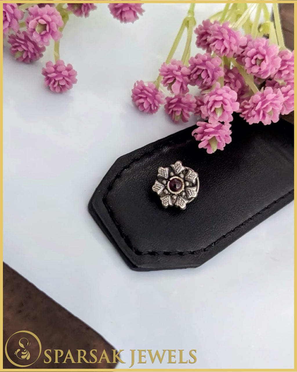 Intricately designed silver temple nosepin with floral motifs on black background