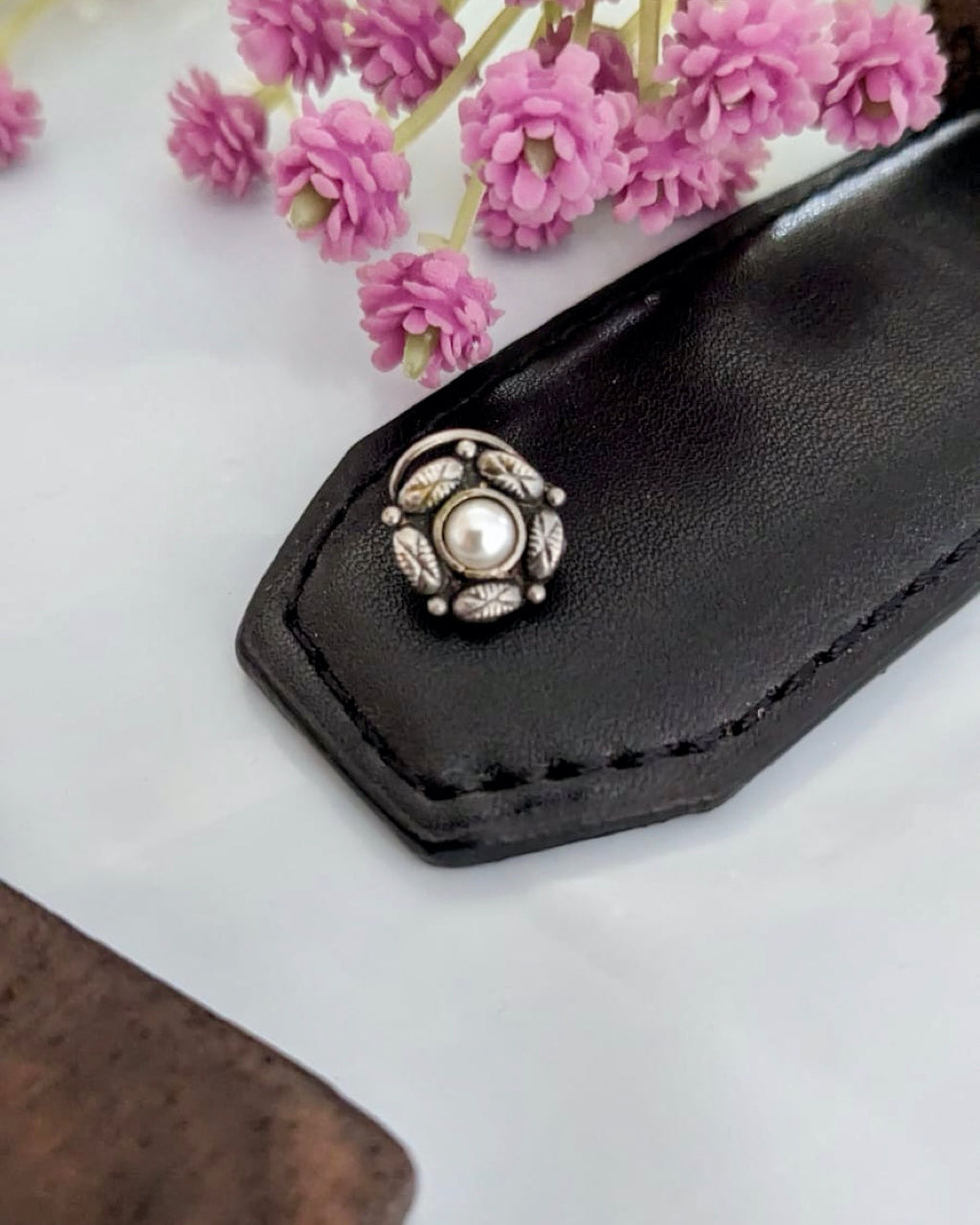 Silver temple nosepin with classic design on pink background