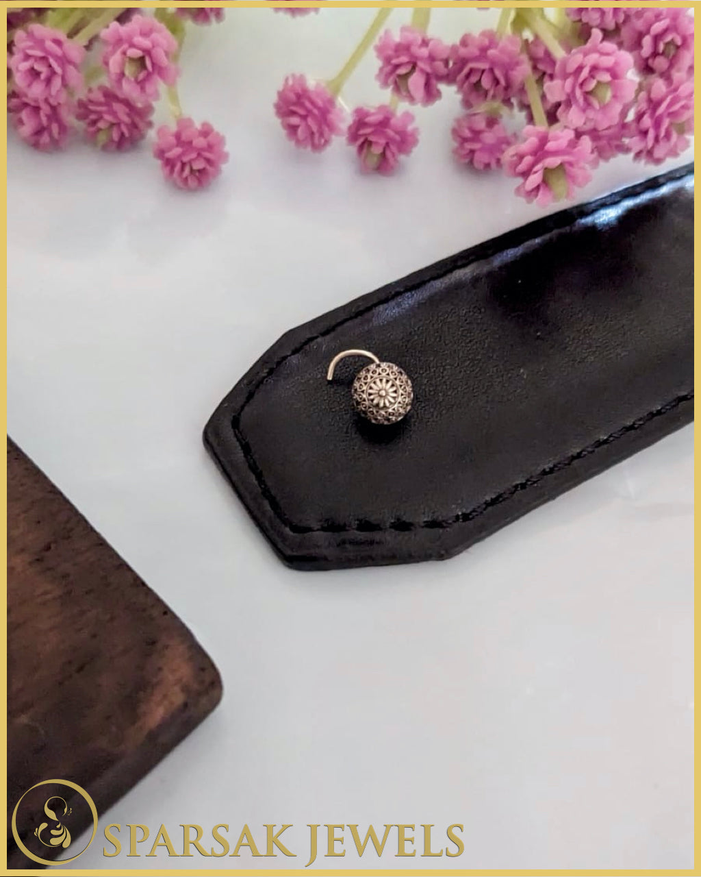 Silver temple nosepin with intricate design on white background