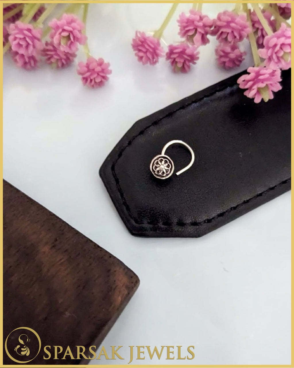 Intricately designed silver temple nosepin with floral motifs on black background