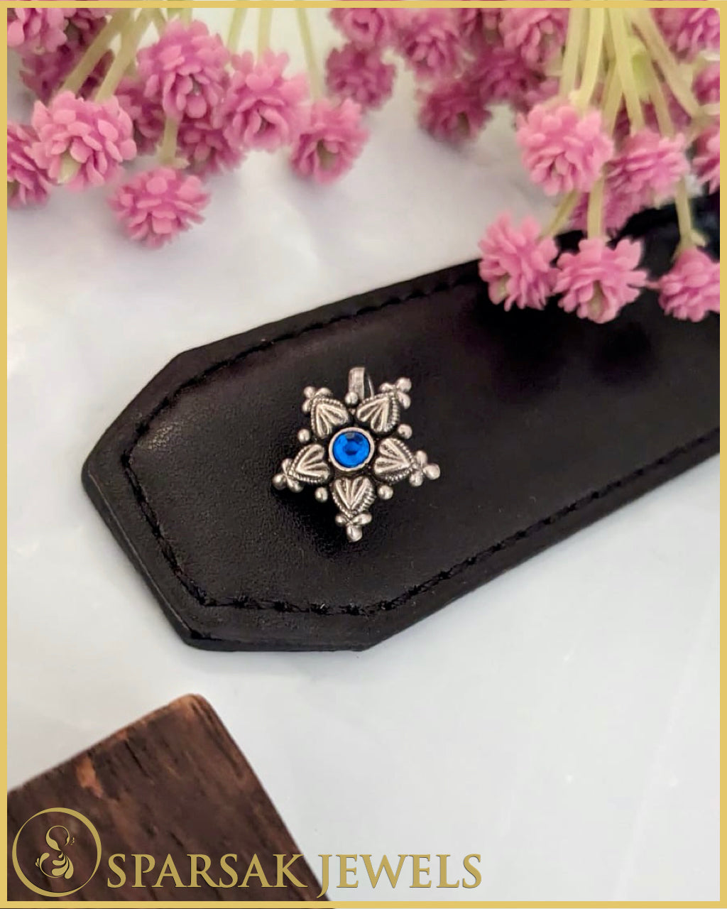 Intricately designed silver temple nosepin with floral motifs on black background