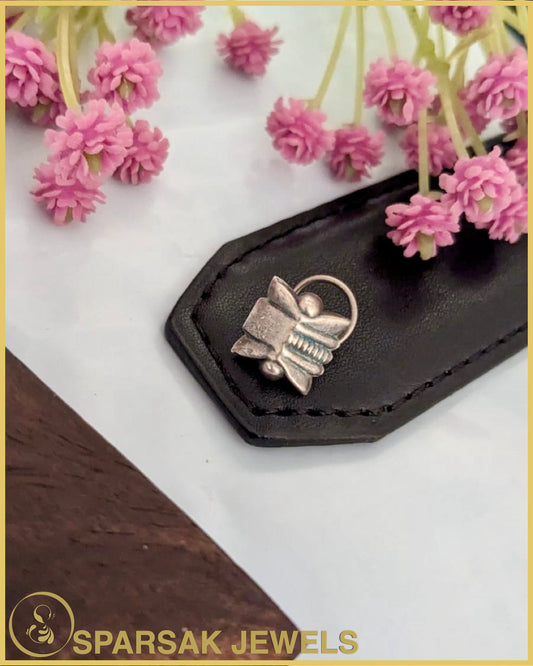 Exquisite silver temple nosepin with floral motifs on pink background