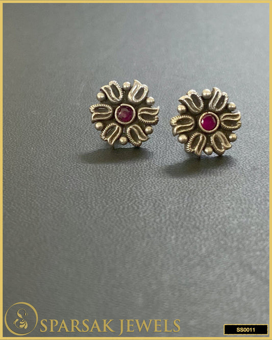 Silver temple earrings studs with traditional patterns on black background.