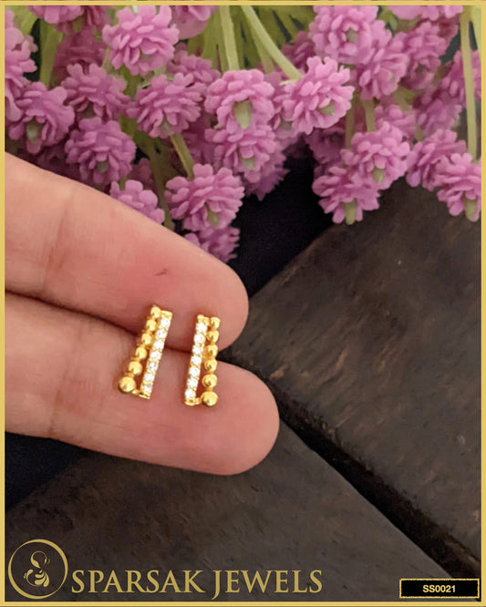 Gold-polished silver stud earrings shining on white background.